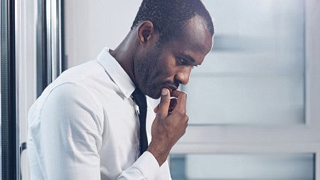 A man sits against a glass wall in thought